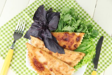 renkli ahşap zemin üzerinde plaka üzerinde taze otlar ile lezzetli chebureks