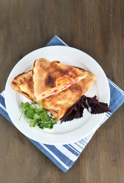 Pizza calzone en plato sobre servilleta sobre mesa de madera — Foto de Stock