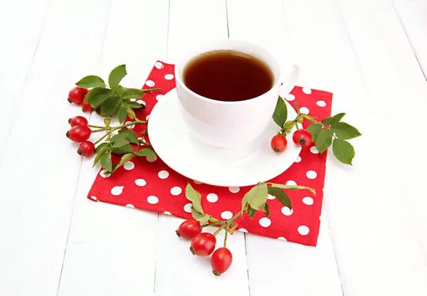 Taza de té con rosas de la cadera, sobre mesa de madera —  Fotos de Stock