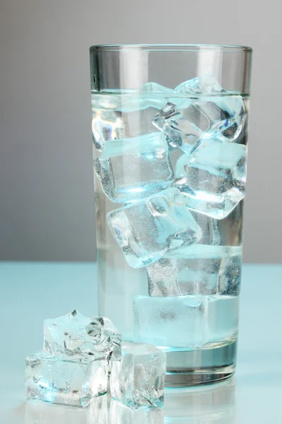 Cubos de hielo en vidrio sobre fondo azul claro —  Fotos de Stock