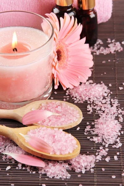 Beautiful pink candle with flower and towel on bamboo mat — Stock Photo, Image