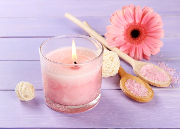 Beautiful pink candle with flower on purple wooden background — Stock Photo, Image