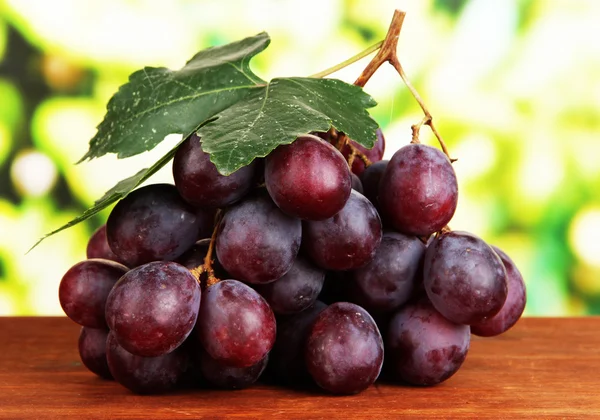 Ripe delicious grapes on table on bright background — Stock Photo, Image