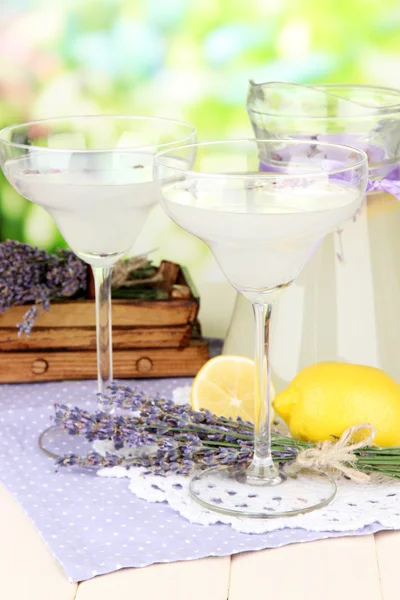 Limonada de lavanda em jarro de vidro e copos de coquetel, em fundo brilhante — Fotografia de Stock