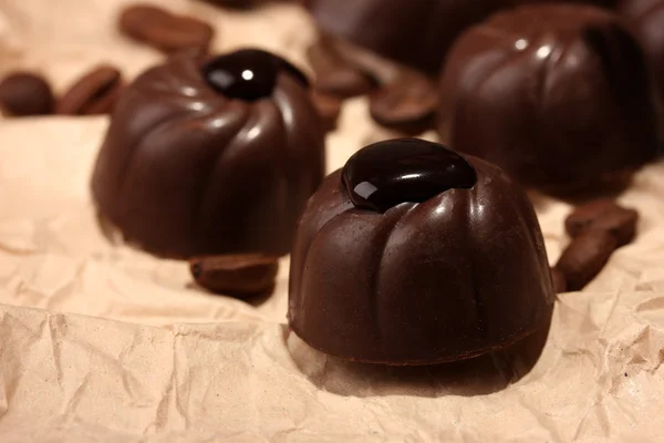 Caramelle al cioccolato e chicchi di caffè, su sfondo di carta beige — Foto Stock