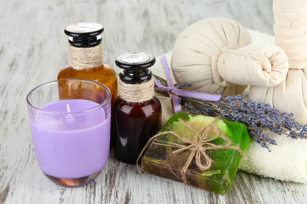 Bodegón con vela de lavanda, jabón, bolas de masaje, botellas, jabón y lavanda fresca, sobre fondo de madera —  Fotos de Stock