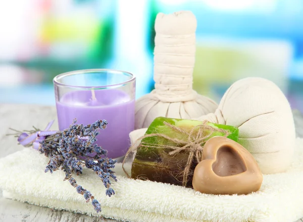 Stilleven met lavendel kaars, zeep, massage ballen, flessen, zeep en verse lavendel, op houten tafel op lichte achtergrond — Stockfoto