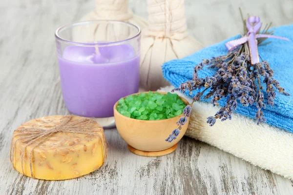 Bodegón con vela de lavanda, jabón, bolas de masaje, botellas, jabón y lavanda fresca, sobre fondo de madera — Foto de Stock