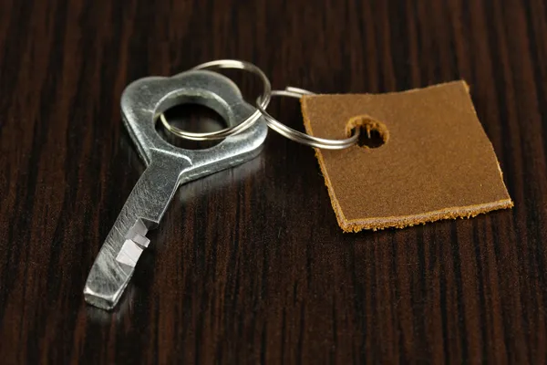 Llave con baratija de cuero sobre fondo de madera —  Fotos de Stock