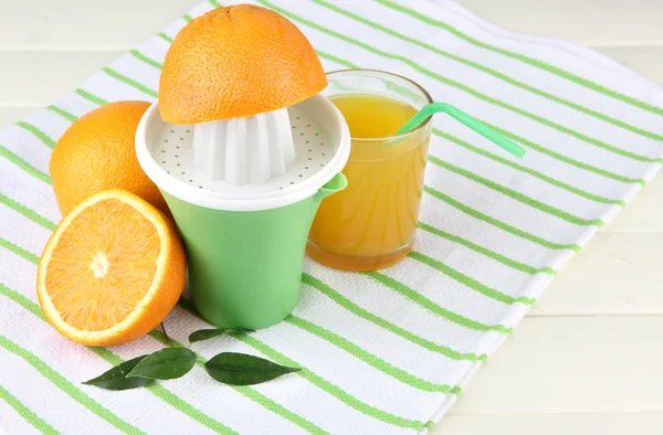 Wyciskarka do cytrusów, kieliszek soku i dojrzałych pomarańczy na biały drewniany stół — Zdjęcie stockowe