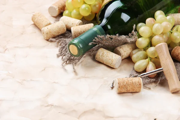 Бутылка вина, винограда и пробок на старом бумажном фоне — стоковое фото