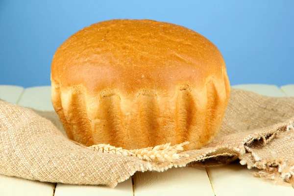 Pão saboroso quente, em pano de saco no fundo de cor — Fotografia de Stock