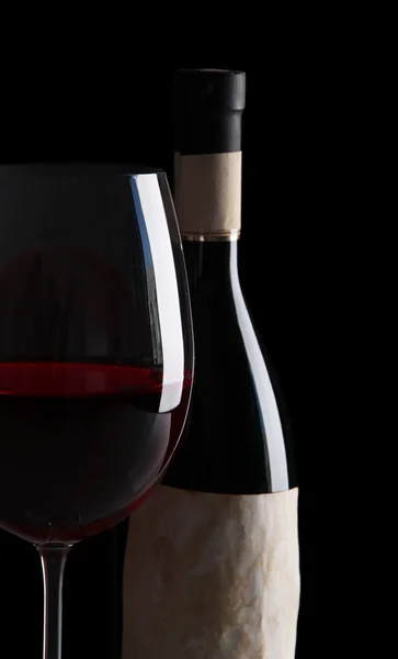 Sklenka vína s lahví na světlé pozadí — Stock fotografie
