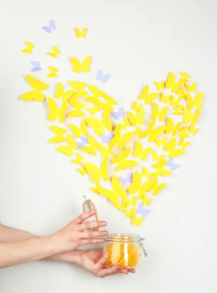 Papír žlutý motýl v podobě srdce fly z banky — Stock fotografie