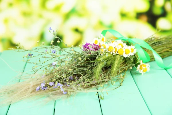 Bouquet of wild flowers and herbs, on wooden table on bright background — Stock Photo, Image