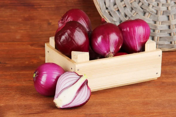 Purple onion in wooden box on wooden background — Stock Photo, Image