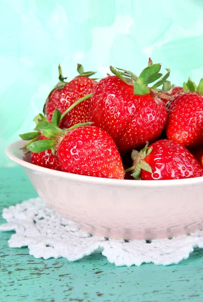 Strawberries in plate on napkin on blue background — Stock Photo, Image