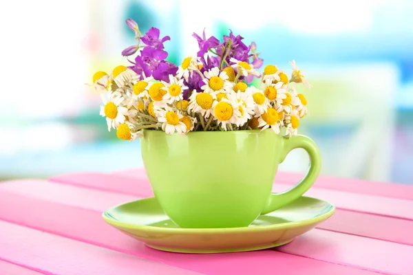 明るい背景上のカップにカモミールの花の花束 — ストック写真