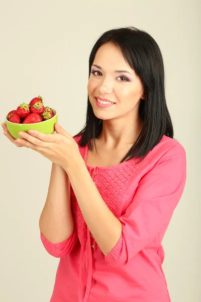 Hermosa joven con fresas sobre fondo gris — Foto de Stock