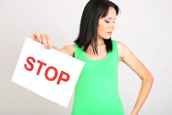 Girl showing stop sign on grey background — Stock Photo, Image