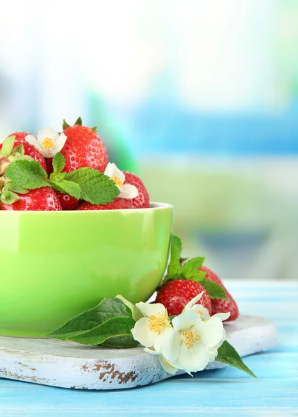 Maturare le fragole dolci in ciotola verde sul tavolo di legno blu — Foto Stock