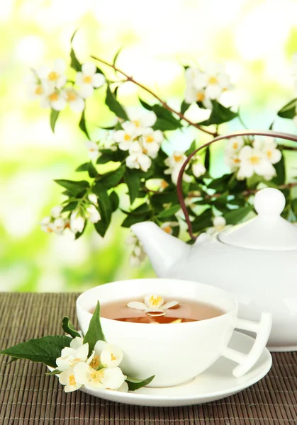 Cup of tea with jasmine, on bamboo mat, on bright background — Stock Photo, Image