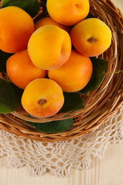 Apricots on wicker coasters on napkin on wooden table — Stock Photo, Image