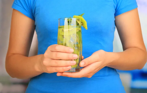 Glass of fruit drink with ice cubes in hand — Stock Photo, Image