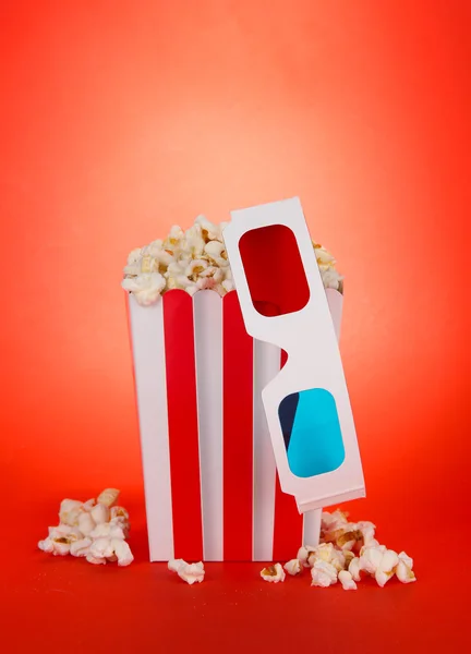 Popcorn und 3D-Brille auf rotem Hintergrund — Stockfoto