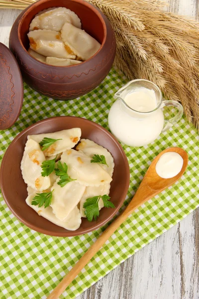 Tasty dumplings with fried onion on brown plate, on wooden background — Stock Photo, Image