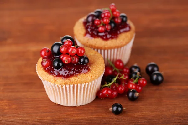 Tasty muffins with berries on wooden background — Stok fotoğraf