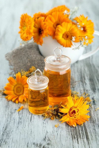 Medizinflaschen und Ringelblumen auf Holzgrund — Stockfoto