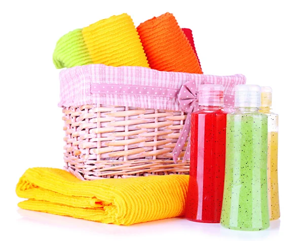 Colorful towels in basket and cosmetics bottles, isolated on white — Stock Photo, Image