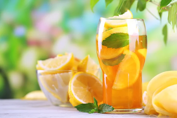 Té helado con limón y menta en la mesa de madera, al aire libre —  Fotos de Stock