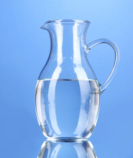 Glaskrug mit Wasser auf blauem Hintergrund — Stockfoto