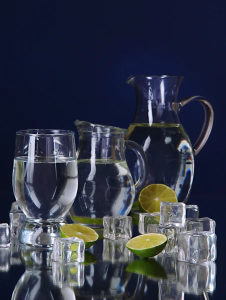 Üveg víz és pohár a kék háttér kancsók — Stock Fotó