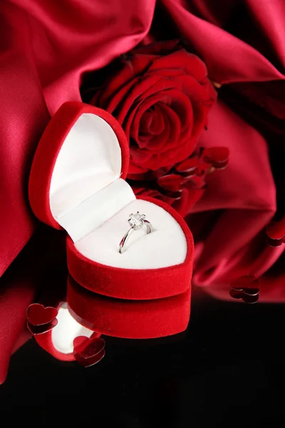 Mooie doos met trouwring en rose op rode zijde achtergrond — Stockfoto