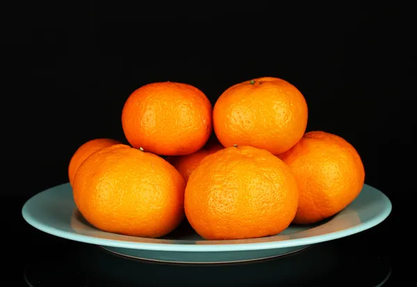 Tasty mandarines on color plate isolated on black — Stock Photo, Image