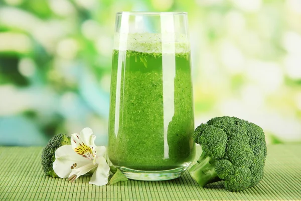 Vaso de jugo de brócoli, sobre estera de bambú, sobre fondo verde — Foto de Stock