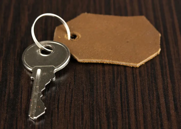 Key with leather trinket on wooden background — Stock Photo, Image