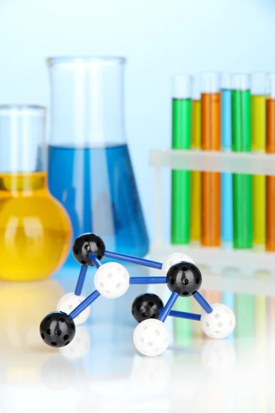 Molekula modell és kémcsövek, kék alapon, színes folyadékkal — Stock Fotó