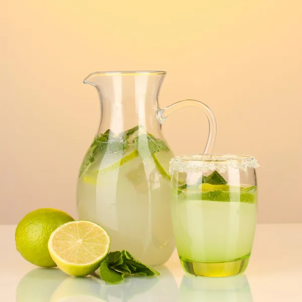 Lemonade in pitcher and glass on yellow background — Stock Photo, Image