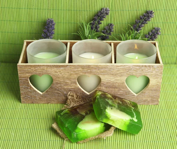 Velas em castiçal de madeira, lavanda e sabão, no tapete verde — Fotografia de Stock