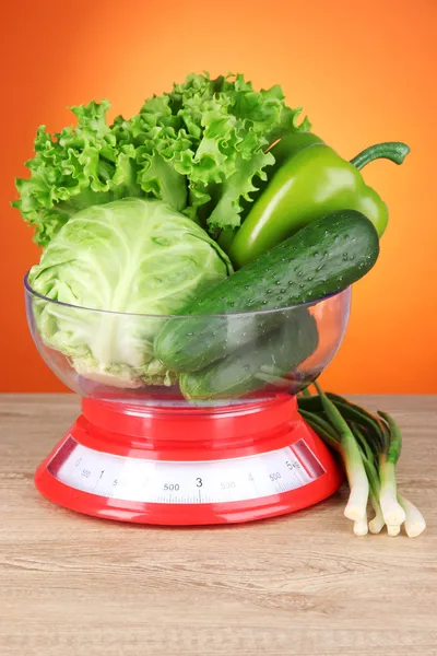 Verse groenten in schalen op tafel op oranje achtergrond — Stockfoto