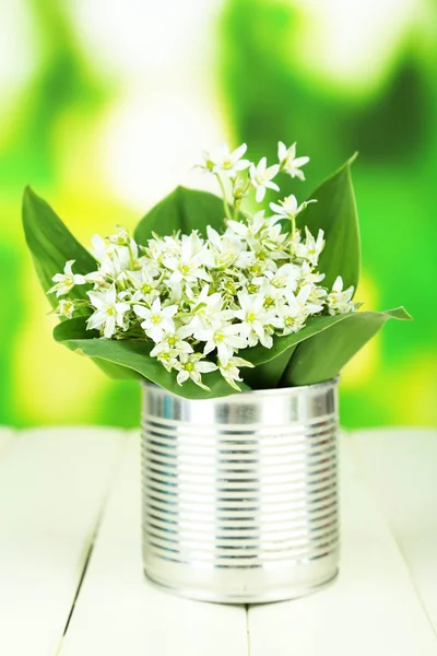Beautiful mountain daffodils in metal can, on wooden table on bright background — Stock Photo, Image