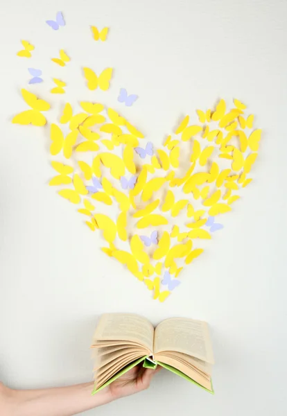 Paper yellow butterfly in form of heart fly out book — Stock Photo, Image