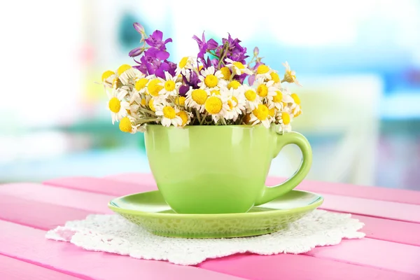 Bouquet of chamomile flowers in cup, on bright background — Stock Photo, Image