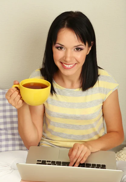 Beautiful young woman sitting with notebook in room — Stock Photo, Image