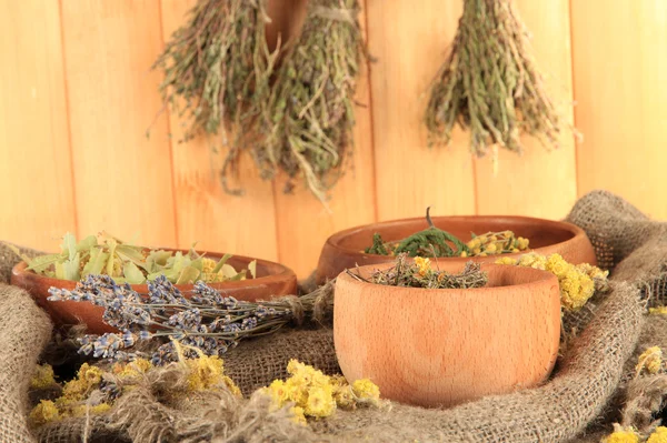 Herbes médicinales dans des bols en bois sur l'ensachage sur la table sur fond en bois — Photo