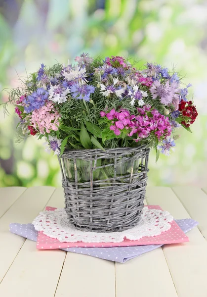 Beautiful bouquet in basket on wooden table on natural background — Stock Photo, Image